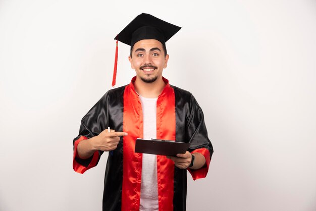 Young graduate student pointing at his diploma on white.