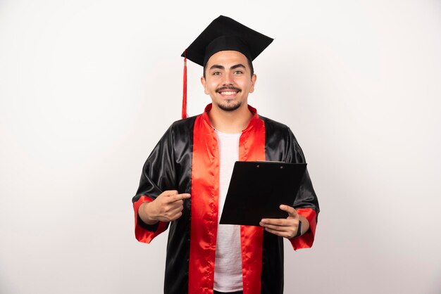 Young graduate student pointing at his diploma on white.