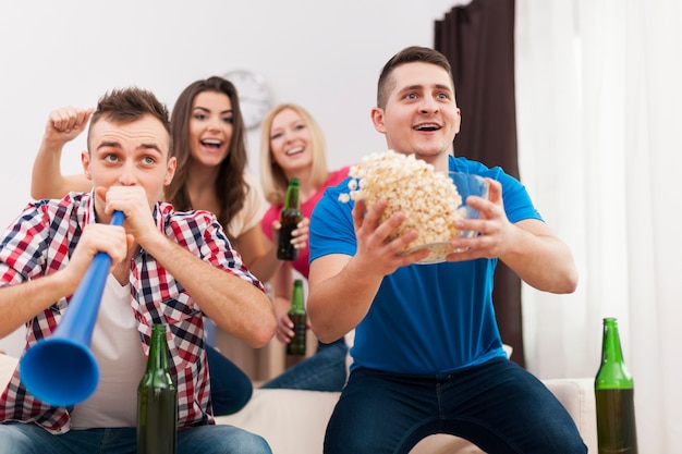 Young group of people celebrating win of favourite sports team