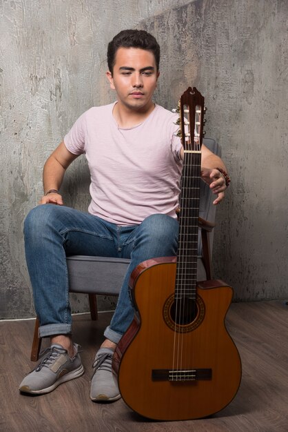 Young guitar player holding the guitar on marble background