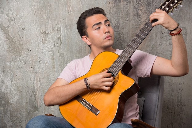 Young guitar player holding the guitar on marble background