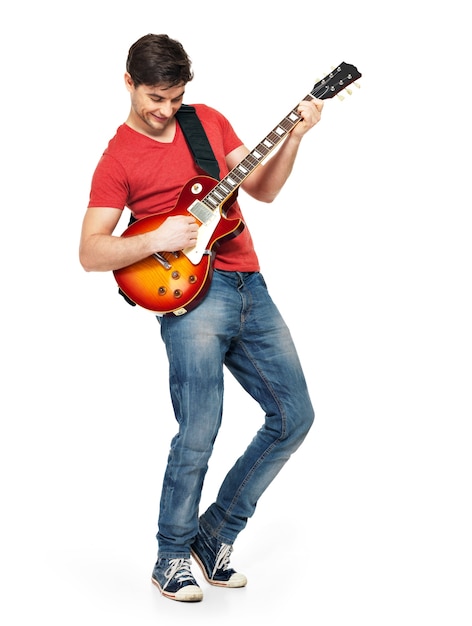 若いギタリストは白い壁に隔離された明るい感情でエレキギターを弾く