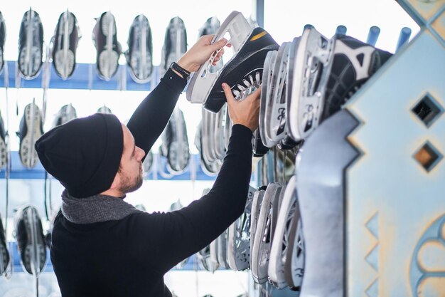 A young guy choosing a pair of skates in a skate hire inside.