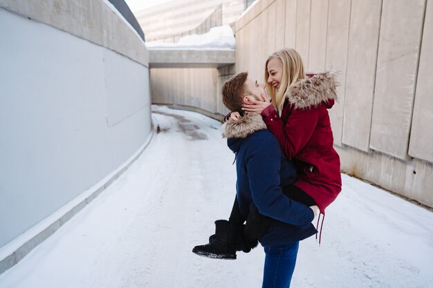 Young guy holds a beautiful girl in his arms.