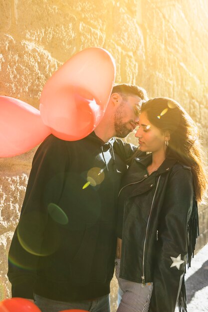 Young guy hugging lady with balloons on street