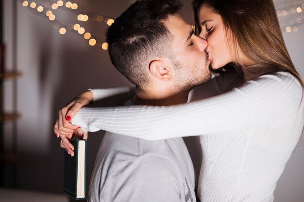 Young guy kissing and hugging lady with book 