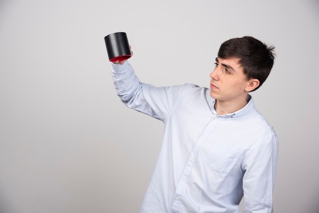 A young guy model in white t-sgirt standing and holding an empty cup