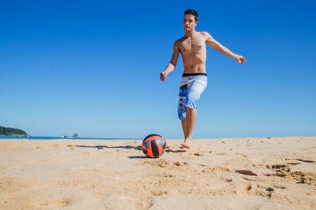 젊은 남자가 해변에서 축구를 연주