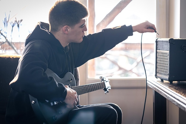 젊은 남자가 그의 방에서 일렉트릭 기타를 연주한다
