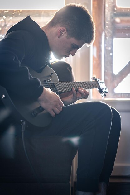 A young guy plays the electric guitar in his room