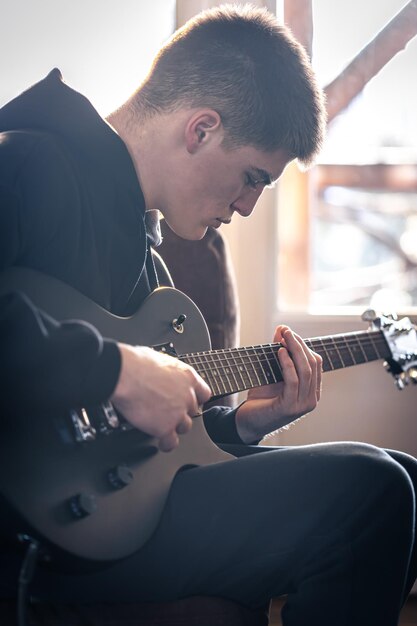 A young guy plays the electric guitar in his room