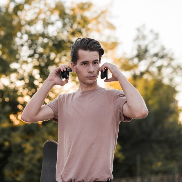 Young guy posing with skateboard and earphones
