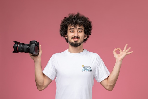 Бесплатное фото Молодой парень показывает нормальный жест и держит фотоаппарат