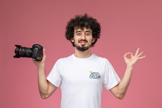 young guy showing okay gesture and holding photocamera