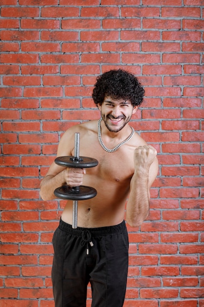 Young guy with lifting dumbbell with one hand.