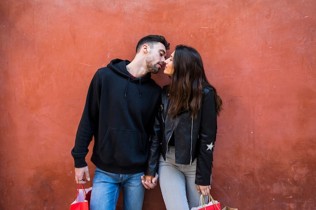 Free photo young guy with packets kissing and holding hands with lady