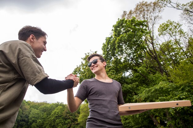 Free Photo young guys shaking hands in nature