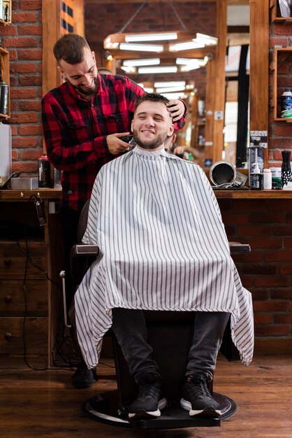 Молодой парикмахер и клиент улыбается