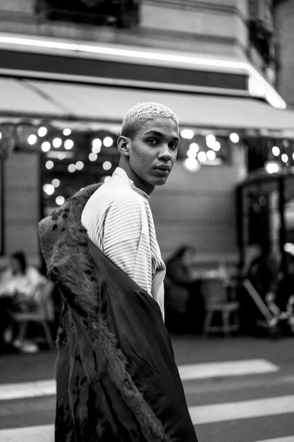 Молодой красивый афроамериканец позирует на улице в Париже. счастливая улыбка, модный стиль. огни вечерних кафе.