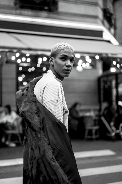 Young handsome african american man posing outdoors in Paris. happy smile, fashion style. lights of evening cafes.