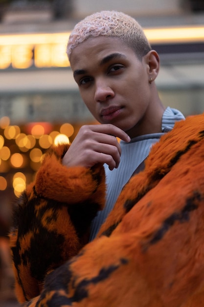 Giovane uomo afroamericano bello che posa all'aperto a parigi. sorriso felice, stile di moda. luci dei caffè serali.