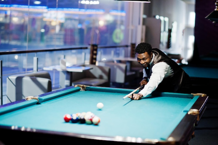 Free Photo young handsome african man wearing white shirt black vest and bow tie play pool billiard