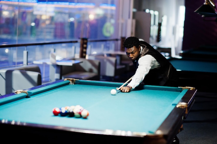 Free Photo young handsome african man wearing white shirt black vest and bow tie play pool billiard