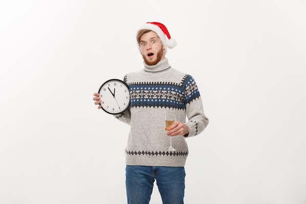 Young handsome beard man in sweater with white clock and champagne on white