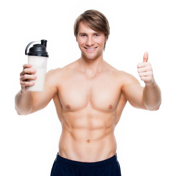 Young handsome bodybuilder with a bottle posing  on a white wall.