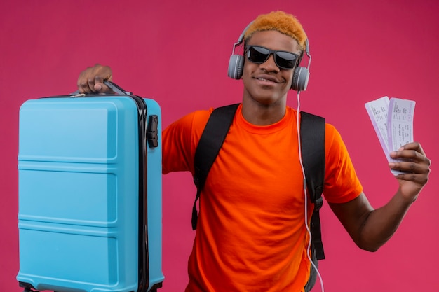 バックパックとヘッドフォンを持っているハンサムな少年旅行スーツケース