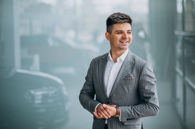 Foto gratuita giovane uomo bello di affari che sceglie un'automobile in una sala d'esposizione dell'automobile