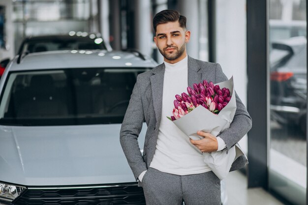 美しい花の花束を提供する若いハンサムなビジネス男