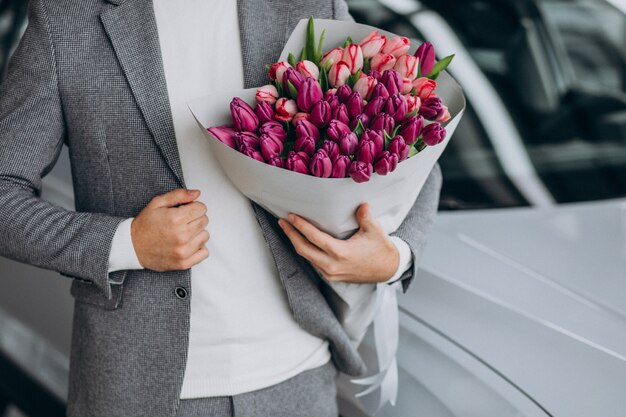 美しい花の花束を提供する若いハンサムなビジネス男