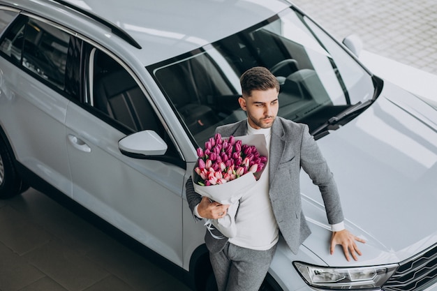 美しい花の花束を提供する若いハンサムなビジネス男
