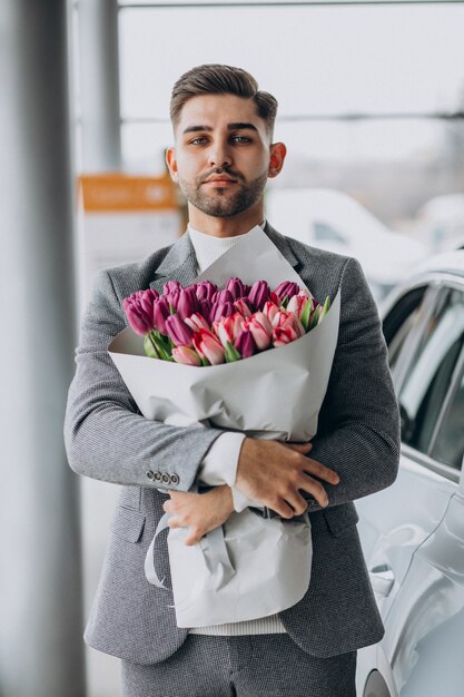 Young handsome business man delivering bouquet of beautiful flowers