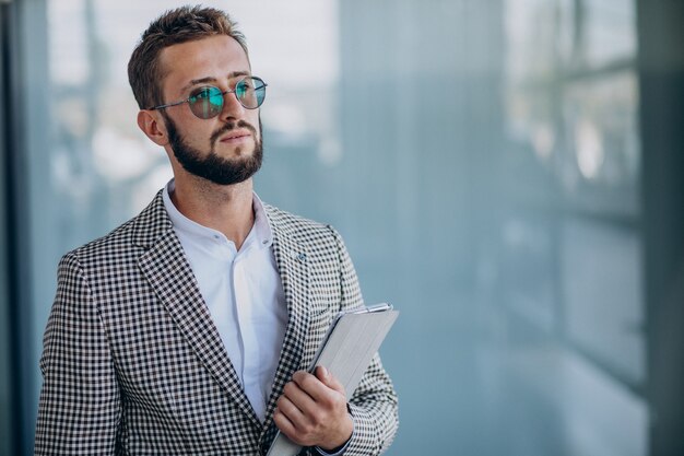 Young handsome business man in office holding tablet