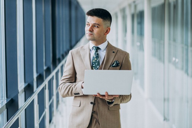 Young handsome business man standing with laptop at the office