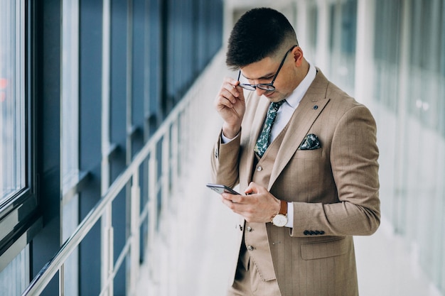Free Photo young handsome business man standing with phone at the office