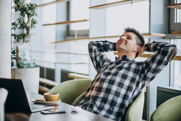 Foto gratuita giovane uomo bello di affari che utilizza computer portatile in un caffè