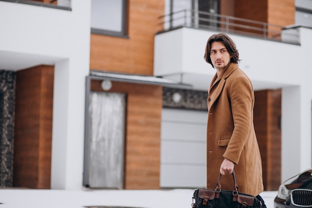 Young handsome businessman walking out of the house to his car