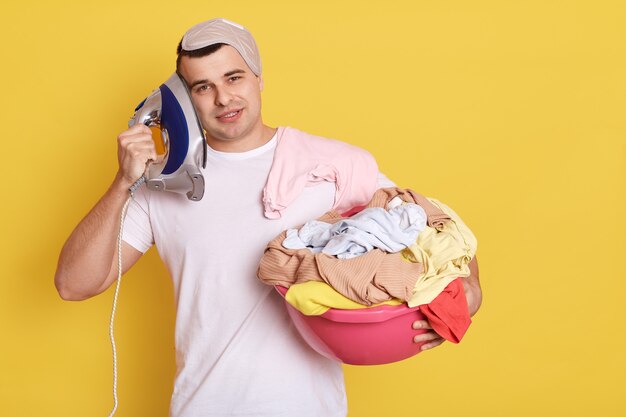 Young handsome Caucasian man holding basin with fresh washed clothes