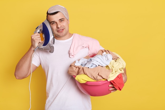 Young handsome Caucasian man holding basin with fresh washed clothes