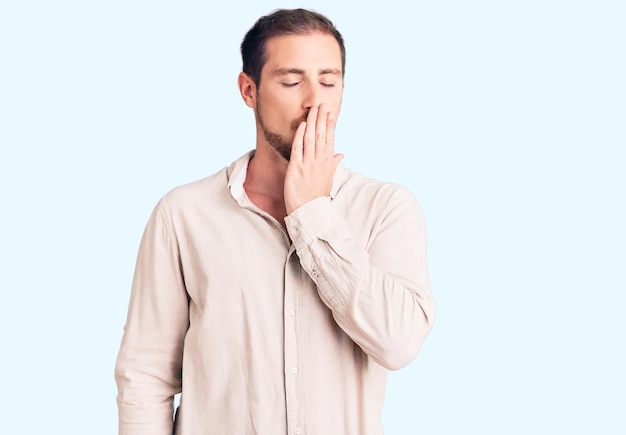 Free photo young handsome caucasian man wearing casual clothes bored yawning tired covering mouth with hand. restless and sleepiness.