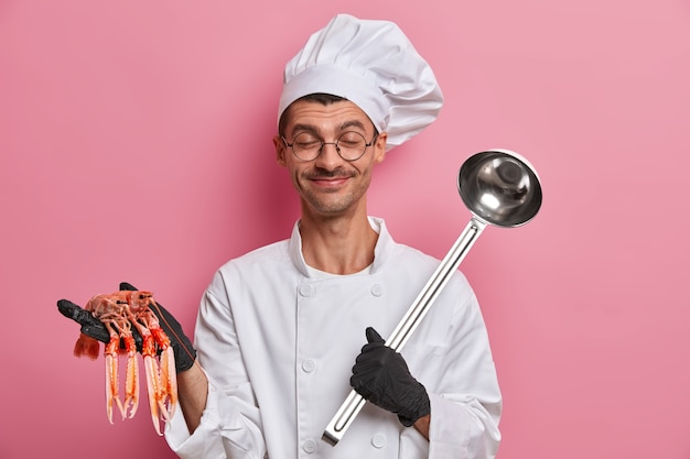 Young handsome chef holding uncooked crayfish isolated