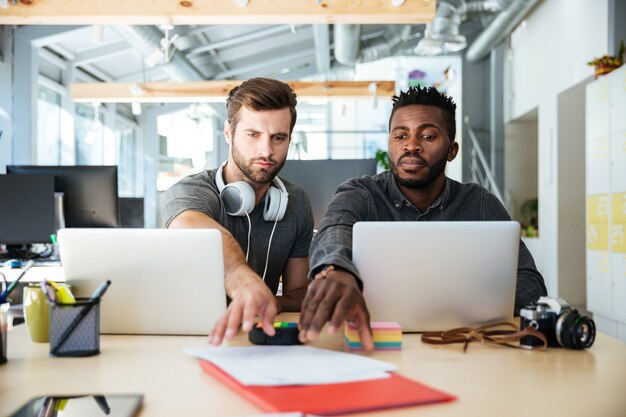 Young handsome colleagues sitting in office coworking