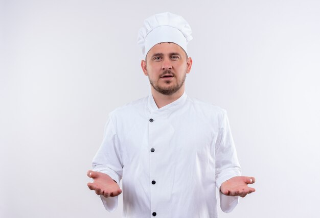 흰색 공간에 고립 된 찾고 빈 손을 보여주는 요리사 유니폼에 젊은 잘 생긴 요리사