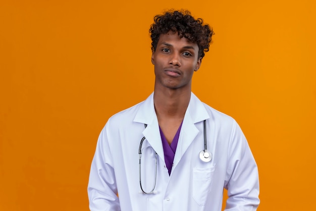 A young handsome dark-skinned man with curly hair wearing white coat with stethoscope  with sad face 