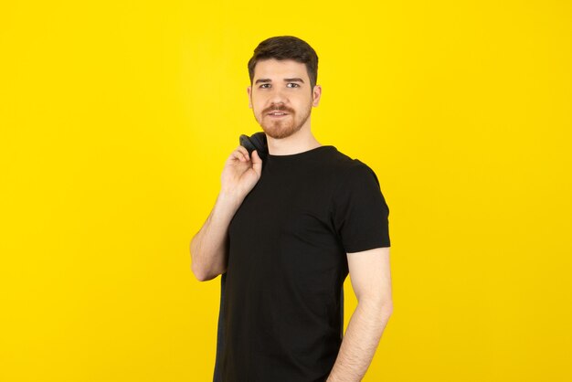 Young handsome guy in a casual wearing looking at camera on a yellow.