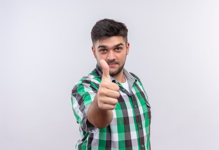 मुफ़्त फोटो young handsome guy wearing checkered shirt looking doing happy thumbs up standing over white wall