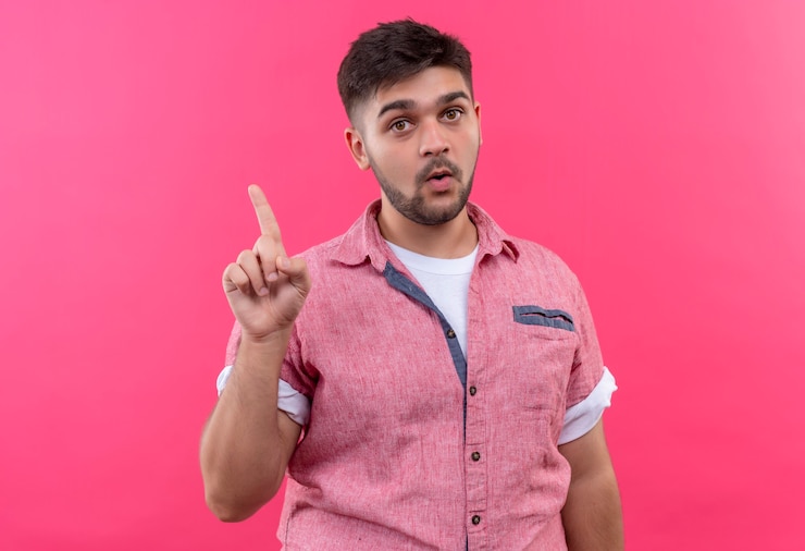 मुफ़्त फोटो young handsome guy wearing pink polo shirt showing idea pointing up with forefinger standing over pink wall
